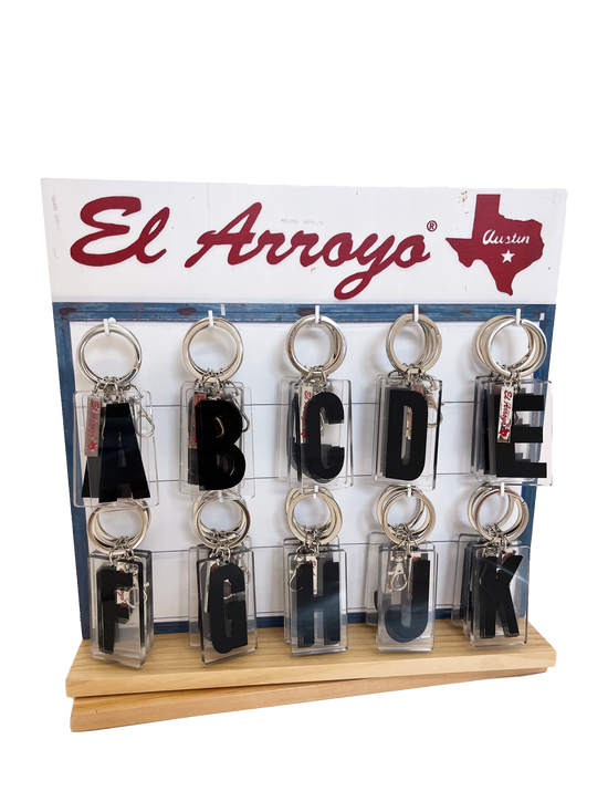 Set of keychains with letters A to L on a display stand with El Arroyo branding.